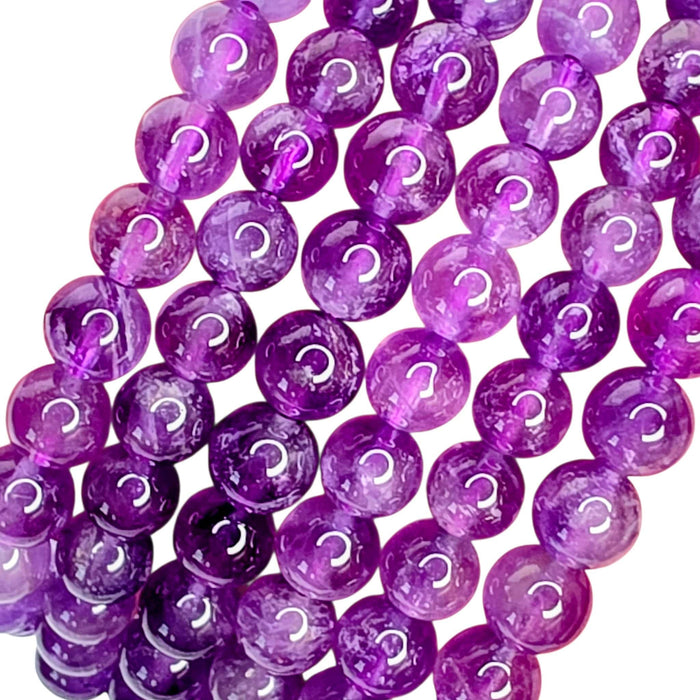 Purple translucent round beads with white question marks, arranged in diagonal strands on a white background.