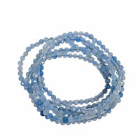 A coiled strand of faceted light blue beads on a plain white background.