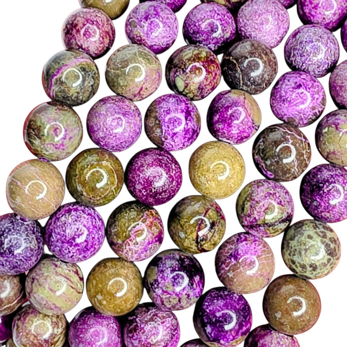 A close-up of round polished gemstone beads with swirling patterns in purple, pink, brown, beige, and olive green on a white background.