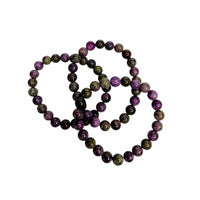 A set of three beaded bracelets made of polished round gemstone beads in purple, green, and black, arranged on a plain white background.