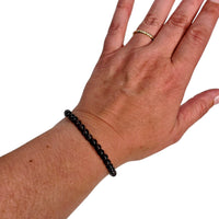 A garnet beaded bracelet worn on a person's wrist, shown against a plain white background. The hand is positioned with the back of the hand facing forward, and a gold ring is visible on one finger.