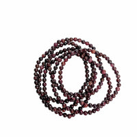 A long strand of polished dark red and black round beads, coiled in a spiral shape against a plain white background.