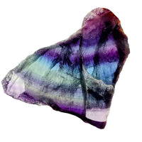 Fluorite slab with layered purple, blue, and green bands on rough surface