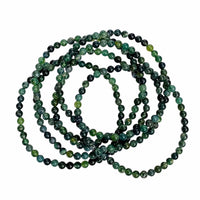 Bunch of moss agate bracelets in a pile on a white background.